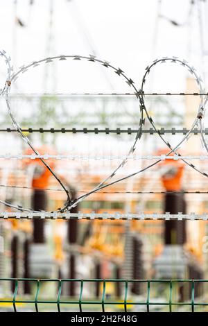 Stacheldraht an einem Zaun, der den Zugang zu einem Umspannwerk einschränkt Stockfoto