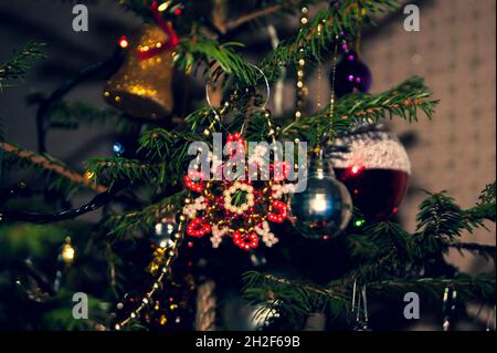 Silvester oder Weihnachten lebhaft elegant dekoriert FichtenNahaufnahme - Weihnachtsspielzeug vor dem Hintergrund von grünen Ästen und Lichtern. Stockfoto