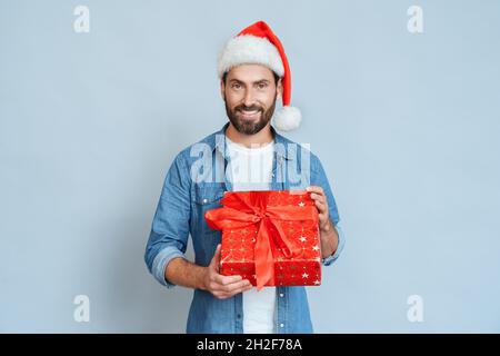 Porträt eines lächelnden Mannes in santa Hut mit Geschenkbox auf blauem Hintergrund Stockfoto