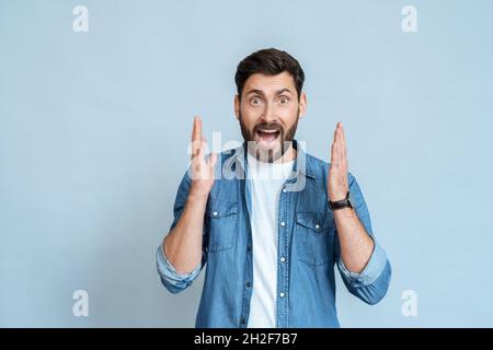 Halbkörperporträt eines überrascht schockierten kaukasischen Mannes mit geöffnetem Mund auf Blau Stockfoto