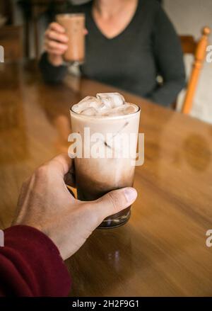 Eiskaffee am Tisch mit einer weißen Frau mittleren Alters Stockfoto