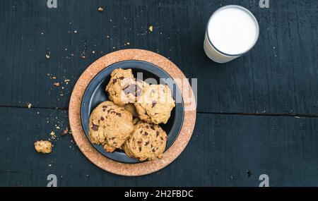 Flache Verlegung von Kochplatte und Milch auf schwarzem Holzhintergrund Stockfoto