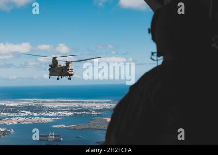 Ein Crew-Chef der US-Armee mit dem 3. Bataillon, dem 25. Luftfahrtregiment, blickt auf eine Boeing CH-47, die am 19. Oktober 2021, Oahu, Hawaii, vom Trainingsgebiet Pohakuloa zurückkehrt. Die Soldaten bedeckten Land, Luft und Meer während der Operation Tropic Voyage im Rahmen des Joint Pacific Multinian Readiness Center Rotation 22-01 und kehrten mit dem Hubschrauber nach Oahu zurück, nachdem sie auf dem United States Army Vessel General Brehon B. Somervell (LSV-3) nach Hawaii Island geflogen waren. (USA Army Fotos von SPC. Rachel Christensen/28th Public Affairs Detachment) Stockfoto