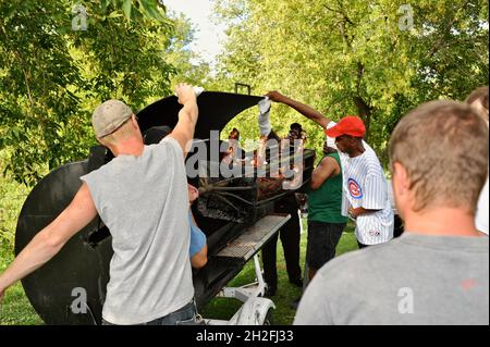 Das schwere, mit Spucken geröstete ganze Schwein auf einen Tisch draußen auf einer Farm im Mittleren Westen in Blanchardville, Wisconsin, USA, zu bringen Stockfoto
