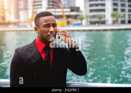 Nahaufnahme Porträt. Schwarzer Geschäftsmann, der am Pier steht und am Telefon spricht und konzentriert aussieht. Geschäftskonzept. Stockfoto