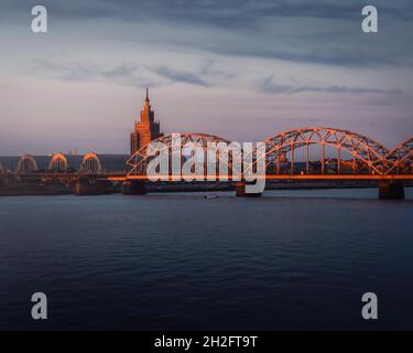 Eisenbahnbrücke und lettische Akademie der Wissenschaften bei Sonnenuntergang - Riga, Lettland Stockfoto