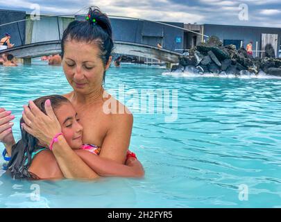 Mutter und Tochter umarmen sich am Pool Stockfoto
