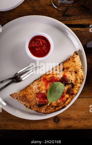 Italienische Calzone mit Marinara-Sauce ganz auf einem Teller Stockfoto