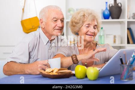 Glückliche ältere Paare, die zu Hause einen Laptop benutzen Stockfoto