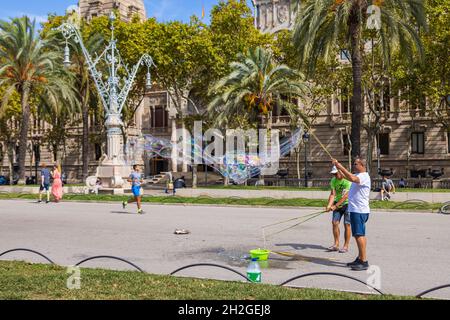 Barcelona, Spanien - 20. September 2021: Zwei Mann machen an einem Spätsommernachmittag auf den Straßen in der Nähe des Arc de Triomf riesige Seifenblasen. Touristen d Stockfoto