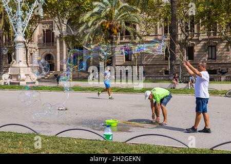 Barcelona, Spanien - 20. September 2021: Zwei Mann machen an einem Spätsommernachmittag auf den Straßen in der Nähe des Arc de Triomf riesige Seifenblasen. Touristen d Stockfoto