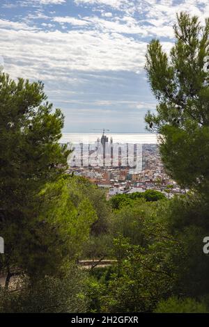 Barcelona, Spanien - 22. September 2021: Blick vom Castell de Montjuic über die Stadt zur Sagrada Familia. Stadtbild durch die Bäume zur Kathedrale Stockfoto