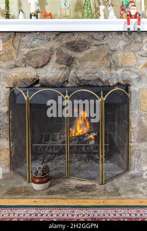 Feuer iit in einem gemütlichen Feldstein Kamin für die Weihnachtsferien dekoriert Stockfoto