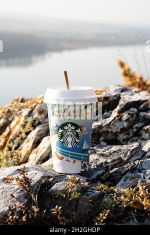 Kemerowo, Russland - 17. Oktober 2021: Starbucks zu gehen Kaffeetasse auf malerischen Hintergrund der Natur. Haselnuss Macchiato Kaffeetasse, Nahaufnahme. Stockfoto