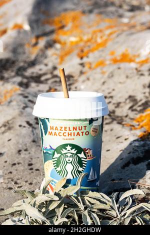 Kemerowo, Russland - 17. Oktober 2021: Starbucks zu gehen Kaffeetasse auf malerischen Hintergrund der Natur. Haselnuss Macchiato Kaffeetasse, Nahaufnahme. Stockfoto