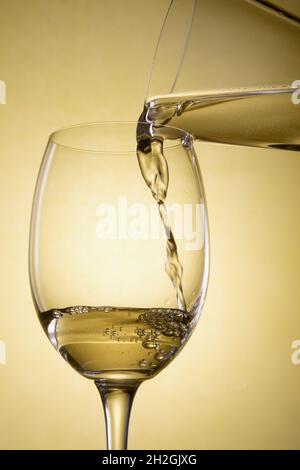 Gießen Sie Weißwein aus einer Karaffe in ein Glas Stockfoto