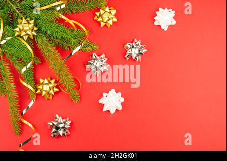 Roter Weihnachtshintergrund des neuen Jahres mit verzierten Fichtenzweigen. goldene Serpentinen, glänzende Dekorelemente. Draufsicht, Kopie des Raumes Stockfoto