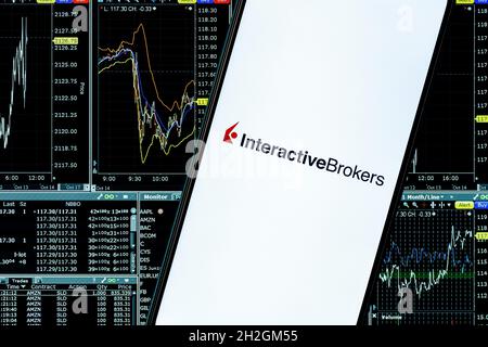 Interactive Brokers ist eine amerikanische Brokerfirma. Ein Smartphone mit dem Interactive Broker-Logo im Hintergrund der Dashboard-Webseite. Stockfoto