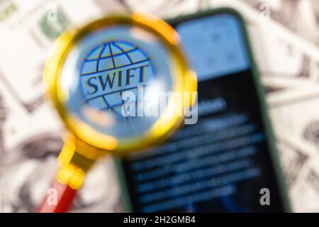 SWIFT ist das Netzwerk der Gesellschaft für weltweite Interbank Financial Telecommunication. SWIFT-Logo auf dem Smartphone-Bildschirm unter der Lupe. Stockfoto