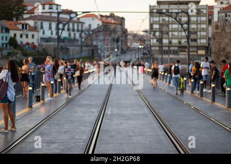 Abstrakte verschwommene Menschen gehen. Die Brücke von Porto Dom Louis ist voll von Touristen, die bei Sonnenuntergang Fotos machen Stockfoto