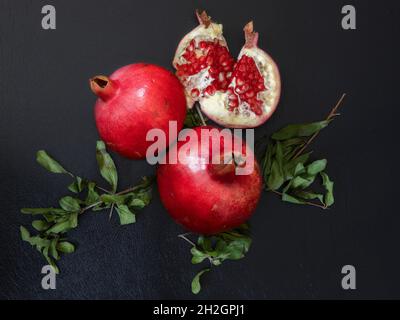 Granatapfelfrüchte mit Zweigen auf schwarzem Hintergrund isoliert Stockfoto