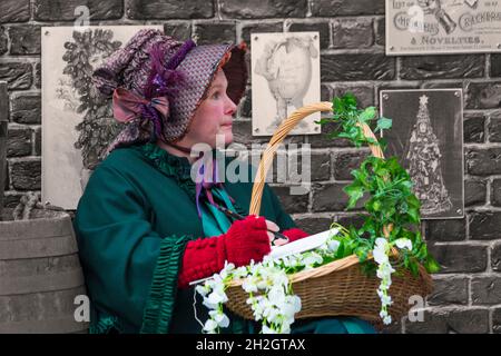 Viktorianische Frau, die im November auf dem Gloucester Quays Victorian Christmas Market in Gloucester, Gloucestershire, einen Korb hält Stockfoto