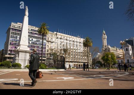 Panoramablick auf einen Mann, der die Plaza de Mayo in Buenos Aires überquert, mit der Pirámide de Mayo, dem ältesten Nationaldenkmal der Stadt, auf der linken Seite Stockfoto