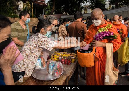 Thailändische buddhistische Anhänger mit Gesichtsmasken bieten dem thailändischen buddhistischen Mönch am Ende der Zeremonie des Buddhistischen Fastentages im Wat SaketBuddhistischer Fastentag ist ein Tag von religiöser Bedeutung für buddhistische Anhänger und markiert den Beginn der dreimonatigen Periode, Der Buddhistische Fastentag in Thailand begann am 25. Juli 2021 und endet am 21. Oktober 2021, als buddhistische Anhänger sich Verdiensten anschließen, um die Rückkehr des Buddha zur Erde zu feiern. Stockfoto