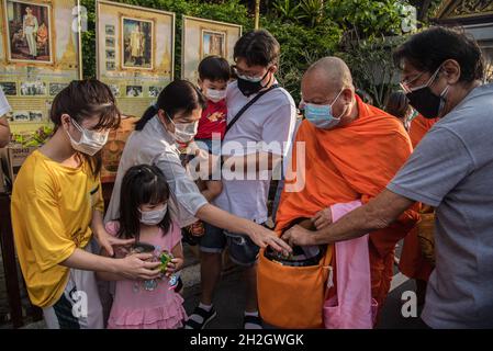 Thailändische buddhistische Anhänger mit Gesichtsmasken bieten dem thailändischen buddhistischen Mönch am Ende der Zeremonie des Buddhistischen Fastentages im Wat SaketBuddhistischer Fastentag ist ein Tag von religiöser Bedeutung für buddhistische Anhänger und markiert den Beginn der dreimonatigen Periode, Der Buddhistische Fastentag in Thailand begann am 25. Juli 2021 und endet am 21. Oktober 2021, als buddhistische Anhänger sich Verdiensten anschließen, um die Rückkehr des Buddha zur Erde zu feiern. (Foto von Peerapon Boonyakiat/SOPA Image/Sipa USA) Stockfoto