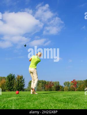 Attraktive weibliche Golfspielerin schlagen Ball aus Tee Stockfoto