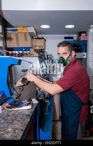 Junger Schuhmacher, der Schuhe in der Werkstatt flicken kann. Stockfoto