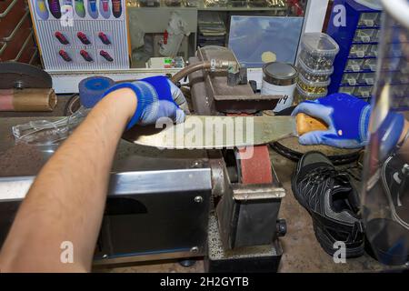 Junger Schuhmacher, der Schuhe in der Werkstatt flicken kann. Stockfoto