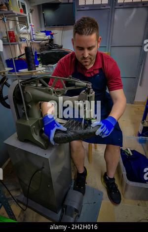 Junger Schuhmacher, der Schuhe in der Werkstatt flicken kann. Stockfoto