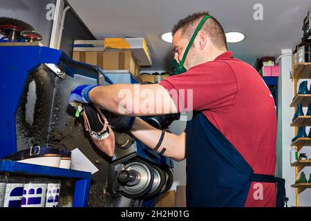 Junger Schuhmacher, der Schuhe in der Werkstatt flicken kann. Stockfoto