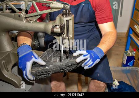 Junger Schuhmacher, der Schuhe in der Werkstatt flicken kann. Stockfoto