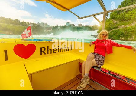 Frau am Boot auf dem Schweizer Wasserfall Rheinfall in der Schweiz bei Sonnenuntergang. 490 m breit und 75 m hoch. Die Kantone Schaffhausen und Zürich Stockfoto