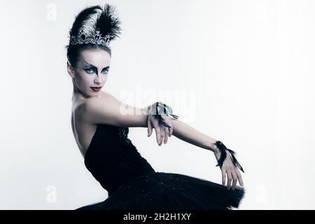 Seitenansicht der jungen Ballerina in schwarzem Tutu, Bühnenkleid und hellem Make-up, isoliert auf weißem Studio-Backgorund Stockfoto