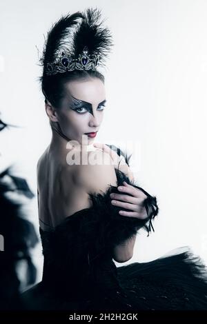 Seitenansicht der jungen Ballerina in schwarzem Tutu, Bühnenkleid und hellem Make-up, isoliert auf weißem Studio-Backgorund Stockfoto
