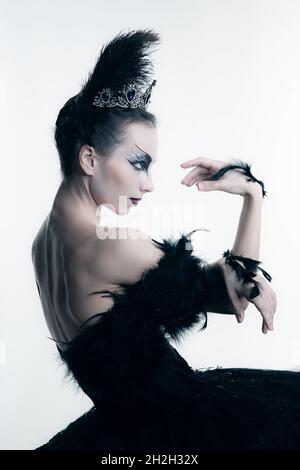 Seitenansicht der jungen Ballerina in schwarzem Tutu, Bühnenkleid und hellem Make-up, isoliert auf weißem Studio-Backgorund Stockfoto