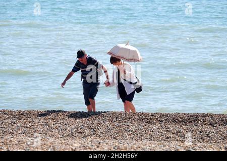Frau mit einem Sonnenschirm, der sich die Hände eines Gentleman am Strand von Eastbourne in Sussex England hält Stockfoto