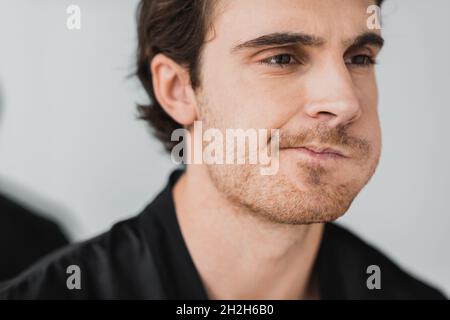 Junger Mann, der den Mund spült und zu Hause wegschaut Stockfoto