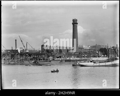 Shot Tower and Lead Works, Belvedere Road, Lambeth, Greater London Authority, 1936. Ein Blick über die Themse in Richtung des Schussturms bei Lambeth Lead Works, der links den Abriss der alten Waterloo Bridge und im Vordergrund ein Ruderboot über den Fluss zeigt. Der Schussturm der Lambeth-Hauptwerke wurde von David Ridall Roper entworfen und 1826 für Thomas Maltby &amp; Co. Erbaut. Zum Zeitpunkt dieser Aufnahme wurde er von Walkers, Parker &amp; Co, aber es wurde später im Jahr 1962 abgerissen, um Platz für die Queen Elizabeth Hall zu machen. Die Waterloo-Brücke, die in Durin gezeigt wird Stockfoto