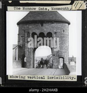 Monnow Bridge and Gate, Monmouth, Monmouthshire, Wales, 1920er- bis 1930er-Jahre. Ein Mann, der ein Pferd und einen Wagen durch das Monnow-Tor führt, mit einem Mann und einem Fahrrad darüber hinaus. Die Überschrift auf dieser Folie lautet: „das Monnow-Tor, Monmouth, zeigt vertikale Unsichtbarkeit.“ Stockfoto