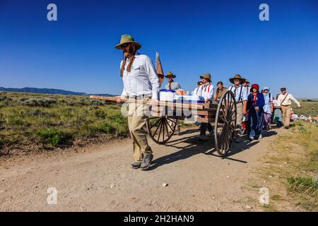 Eine Gruppe von jungen Leuten und Führern im Teenageralter reenact eine mormonische Pionierhandkarren-Wanderung auf den Ebenen von Wyoming. Stockfoto