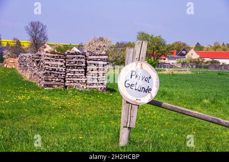 Symbolbild: Wiesengrundstück mit Holzstapeln und Schild Privatgelände. Stockfoto