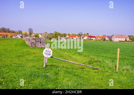 Symbolbild: Wiesengrundstück mit Holzstapeln und Schild Privatgelände. Stockfoto