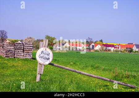 Symbolbild: Wiesengrundstück mit Holzstapeln und Schild Privatgelände. Stockfoto