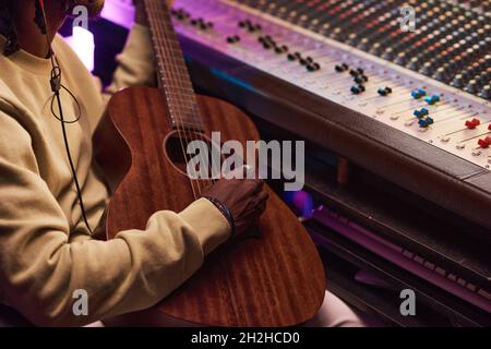 Nahaufnahme eines afrikanischen Musikers, der während seiner Arbeit im Musikstudio Gitarre spielt Stockfoto