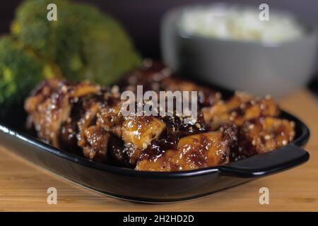 Konzentrieren Sie sich selektiv auf gekochtes Huhn neben Brokkoli mit einer Schüssel Reis im Hintergrund Stockfoto