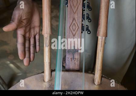 SENEGAL, Benediktinerkloster Keur Moussa, Mönche arbeiten in der Werkstatt, um die afrikanische Kora-Brückenharfe zu bauen, Branding mit Kreuz und Zahl Stockfoto